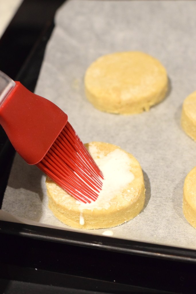 brushing heavy cream on biscuits